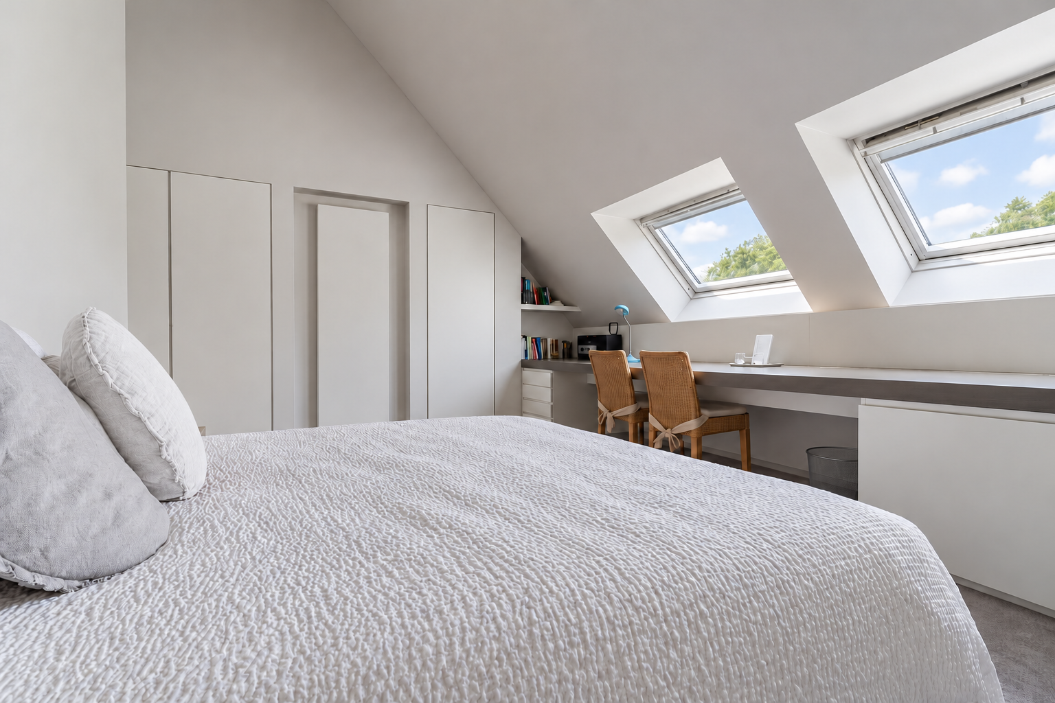 Kamer Tuin met wit opgemaakt tweepersoonsbed en twee dakramen met zicht op bomen en blauwe lucht