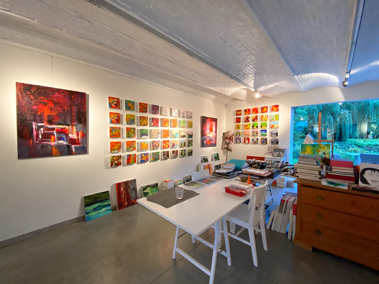De werkplek in het atelier: schilderijen aan de muur rond een grote werktafel