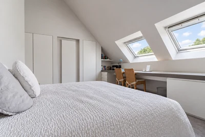 Kamer Tuin met wit opgemaakt tweepersoonsbed en twee dakramen met zicht op bomen en blauwe lucht